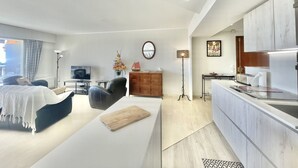Une chambre d’hôtel moderne dotée d’un canapé, d’un coin repas, d’une cuisine et d’une grande fenêtre.