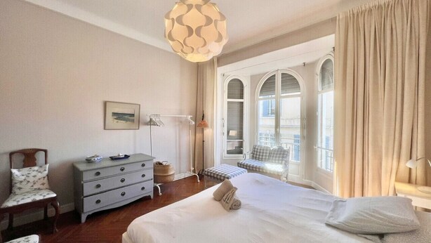 A hotel bedroom with a large bed, a dresser, a chair, and a balcony with curtains. - Novembre,10 minuts from Palais (Cannes)