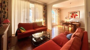 A living room with a red sofa, a coffee table, and a dining area with a table and chairs. - Novembre,10 minuts from Palais (Cannes)