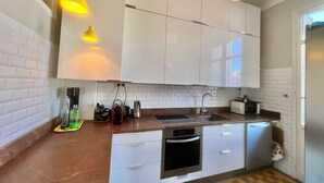 A modern kitchen with white cabinets, a stainless steel sink, and a built-in oven. There are pendant lights above the counter and a coffee machine on the counter. - Novembre,10 minuts from Palais (Cannes)