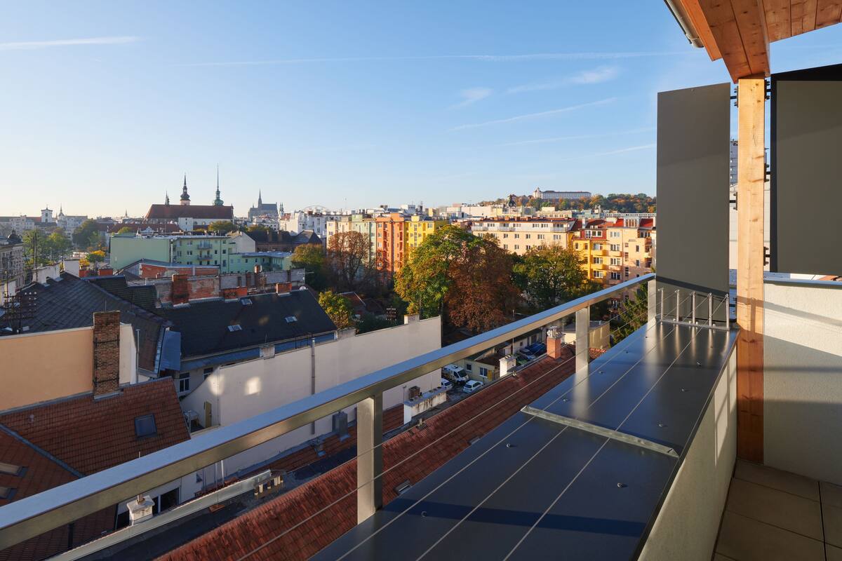 A balcony with a view of a cityscape, including buildings and trees.