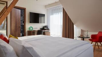 Una habitación de hotel con una cama grande, un escritorio con computadora, un televisor y una silla roja.