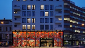 Un hotel con fachada moderna, varios balcones y ventanas iluminadas.