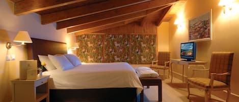 Une chambre à coucher avec un grand lit, un bureau avec un ordinateur, une chaise et un mur recouvert d’un papier peint à motifs.