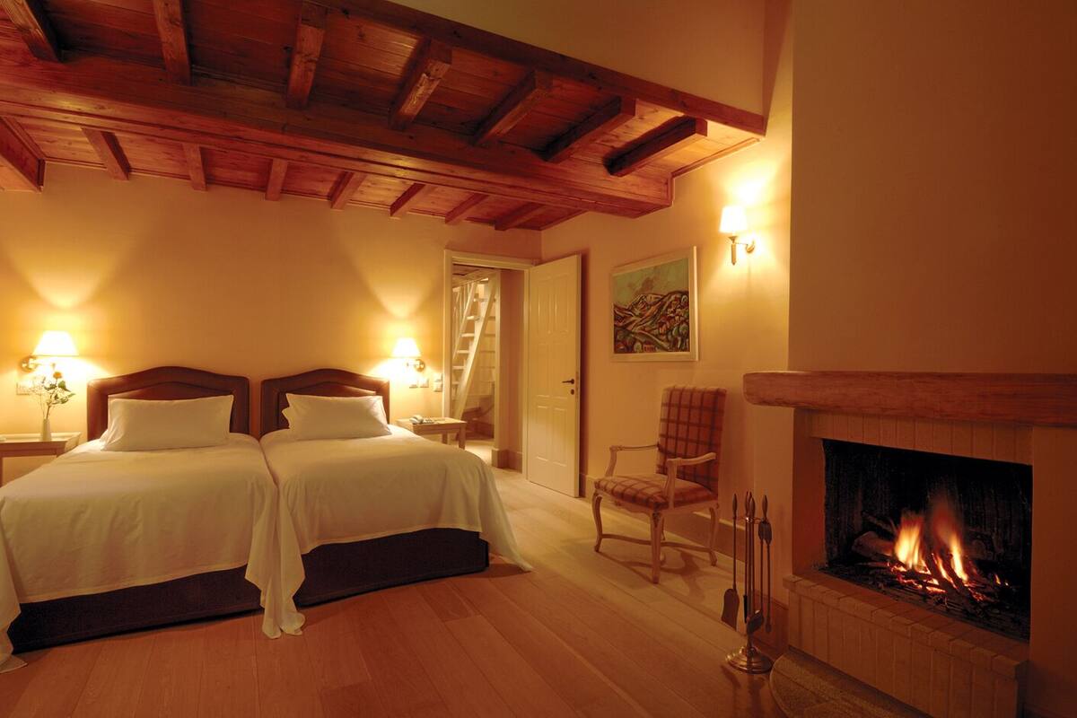 A hotel room with two beds, a fireplace, and a staircase leading to another room.