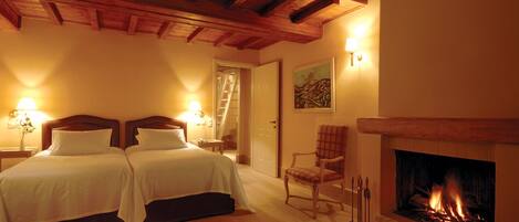 Habitación de hotel con dos camas, una chimenea y una escalera que lleva a otra habitación.