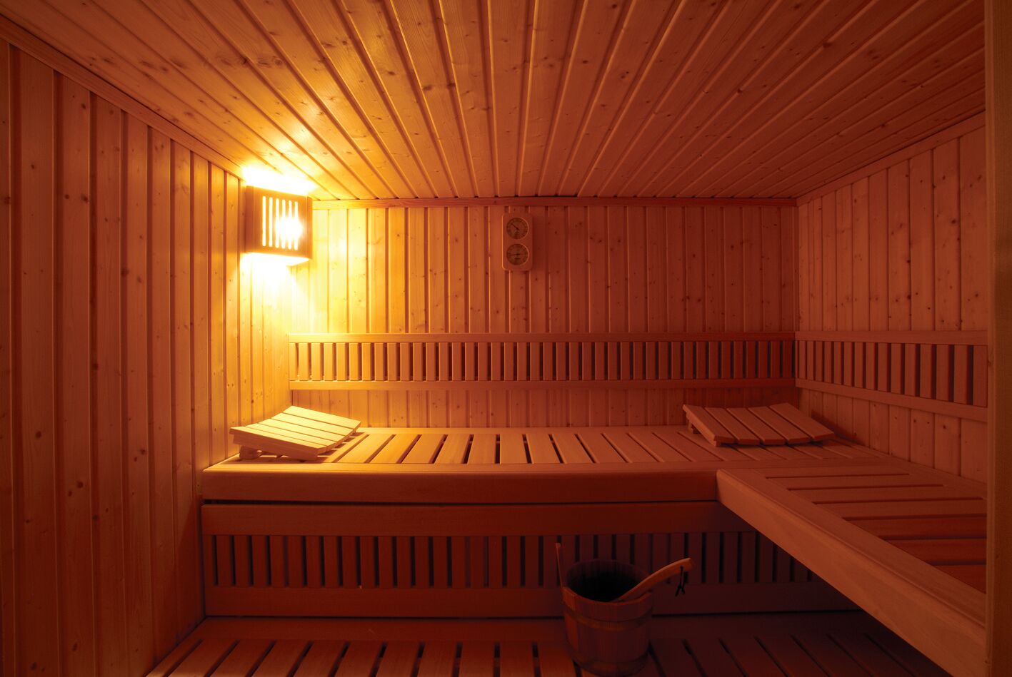 A wooden sauna with benches and a wall-mounted light.