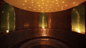 A circular room with mosaic walls and ceiling, featuring recessed lighting and a central light source.
