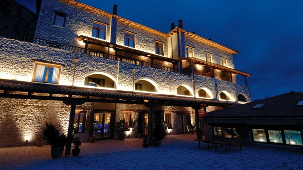 A stone building with multiple windows and balconies, illuminated by warm lighting.