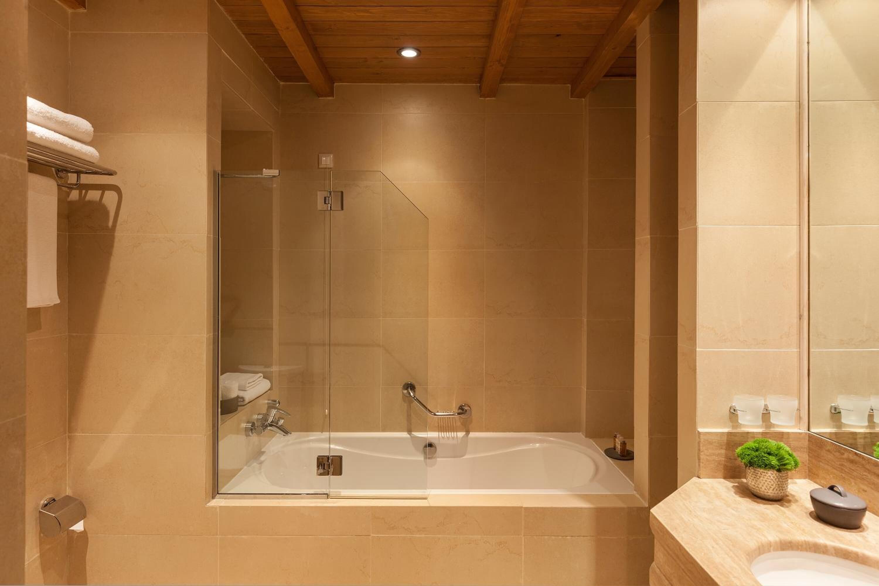 A modern bathroom with a glass-enclosed shower, a large bathtub, and a vanity with a mirror.