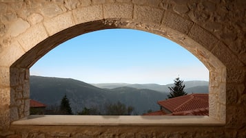 A stone arch window overlooking a mountainous landscape with a clear sky.