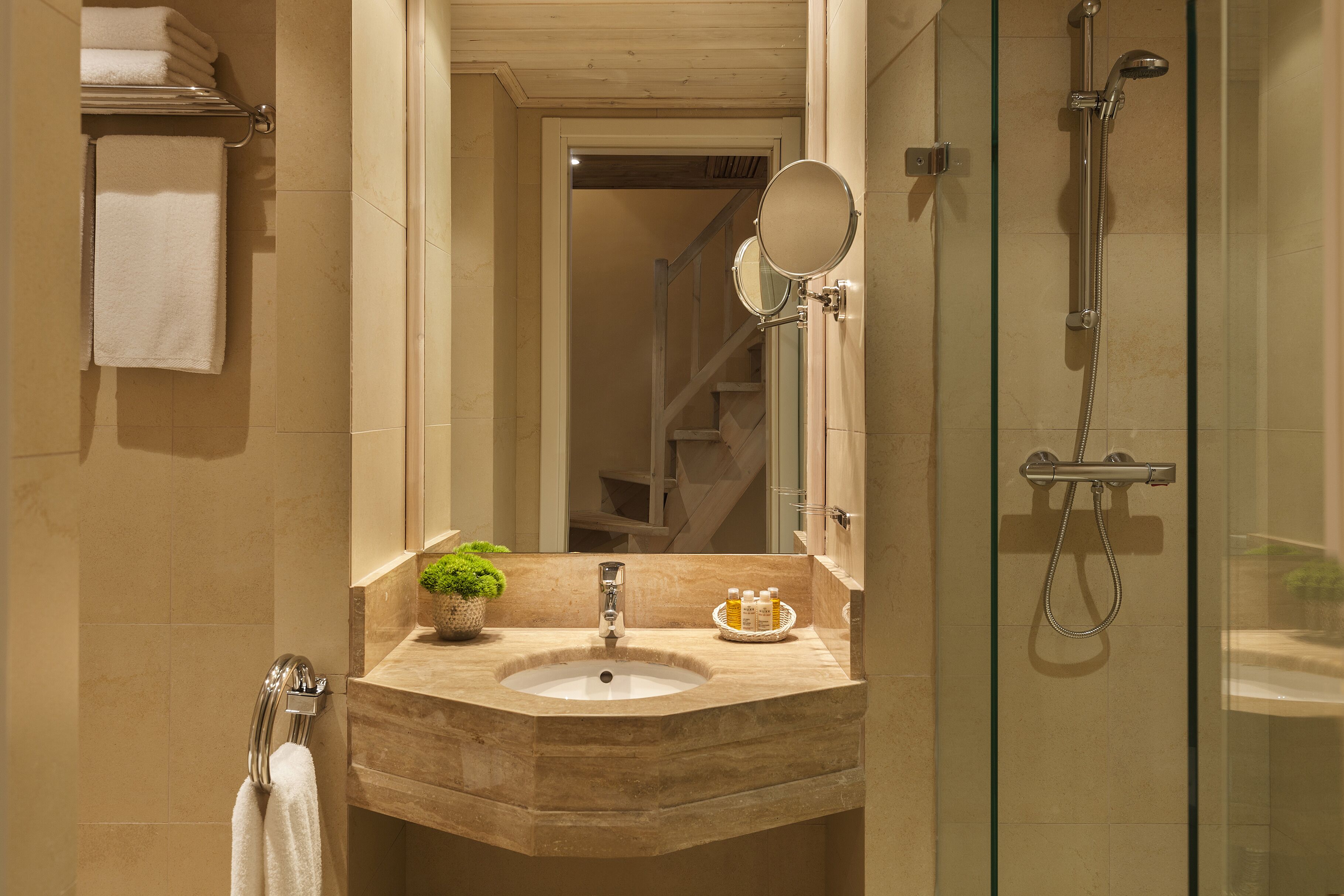 A bathroom with a marble sink, a glass-enclosed shower, and a mirror above the sink.