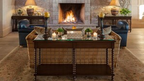 A cozy lobby with a stone fireplace, a chandelier, and leather sofas.