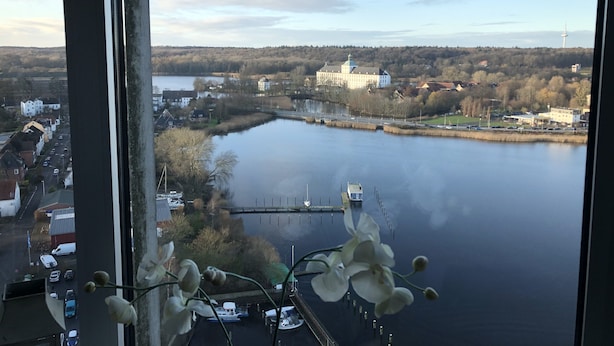 Blick auf einen Fluss mit einer Brücke, Gebäuden und einem großen weißen Bauwerk am gegenüberliegenden Ufer.