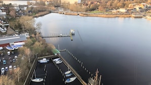 Ein Yachthafen mit mehreren vor Anker liegenden Booten, ein großes Gebäude im Hintergrund und ruhiges Gewässer.