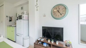 Uma sala de estar moderna com uma TV de tela plana, painel de entretenimento de madeira e um relógio de parede grande.