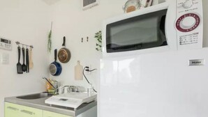 Uma cozinha com micro-ondas, cafeteira e chaleira no balcão.