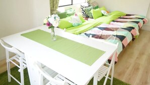 Quarto com uma mesa branca, um jogo americano verde e uma cama com roupa de cama colorida.
