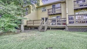 A multi-story building with balconies, a wooden deck, and a grassy yard. - DF109- Centrally located in Canaan Valley! Pool! (Davis)