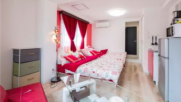 A compact bedroom with a bed, a bedside table, a lamp, a wardrobe, and a kitchenette. - Not Ninja Kyocera Dome 1 - 5th Floor Room (Osaka)