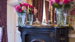 A fireplace with a mantel decorated with vases of flowers and candles, set against a floral wallpaper background. - Hotel Minella (Clonmel)