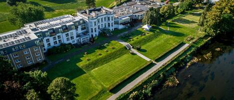 Vista aérea de un edificio grande e histórico con varias secciones, un patio central y un río junto a la propiedad.