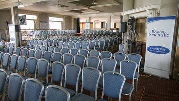 A conference room with rows of blue chairs, a banner for Boston Scientific, and a camera on a tripod.