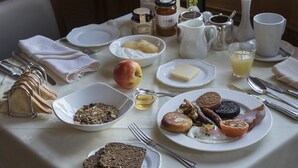 A breakfast table set with various food items, including bread, eggs, and butter, in a room with a window and a sign reading "Tipperary Food Producers". - Hotel Minella (Clonmel)