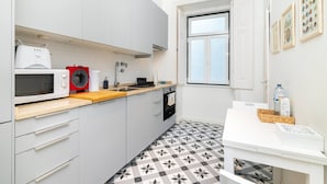 A compact kitchen with a microwave, a red appliance, a sink, and a window with a view.