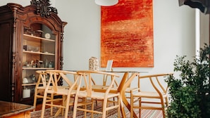 A dining area with a wooden table and chairs, a dark wooden cabinet, and a large red abstract painting on the wall.