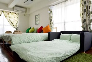 A room with two beds, a sofa, and a green rug.