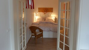Une chambre à coucher avec un lit, une chaise et un plancher en bois.