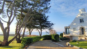 A white house with a stone foundation, a balcony, and a view of the ocean. - Villa FEUNTEUN on the ocean! (Clohars-Carnoët)