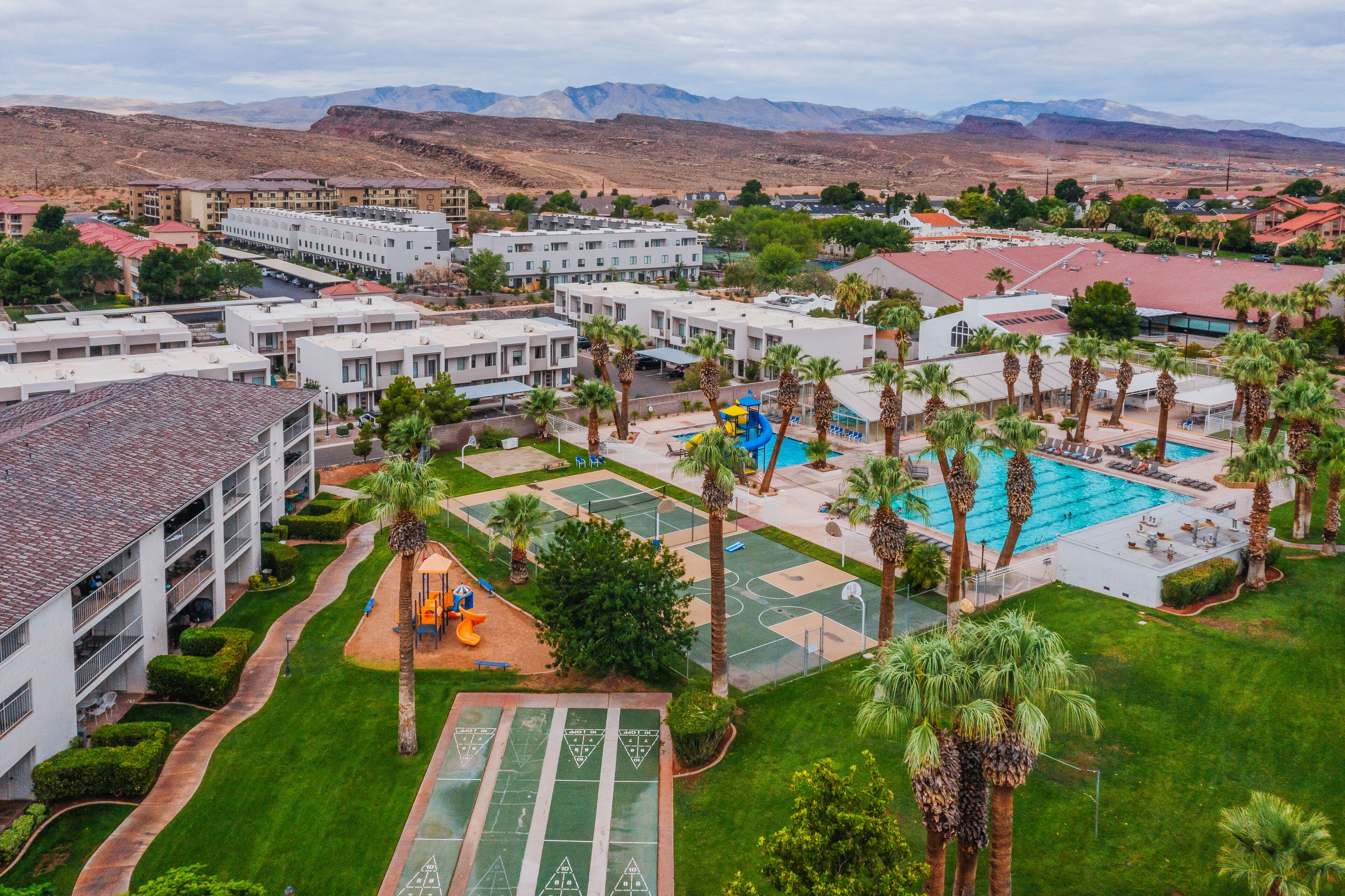 An aerial view of a resort with multiple buildings, a swimming pool, and a tennis court.