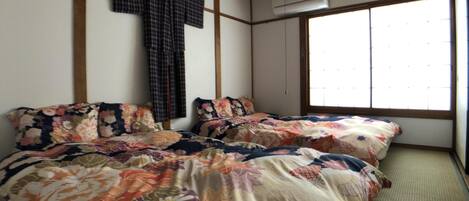 Una habitación con una cama, una cruz en la pared y una ventana.