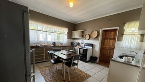 A compact kitchen with a dining area, a refrigerator, a microwave, an oven, and a sink.