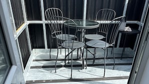 A patio area with a table and chairs, a striped floor, and a door leading to the interior. - 59a Whitstable - 1 Bedroom Flat, Balcony & Parking (Whitstable)