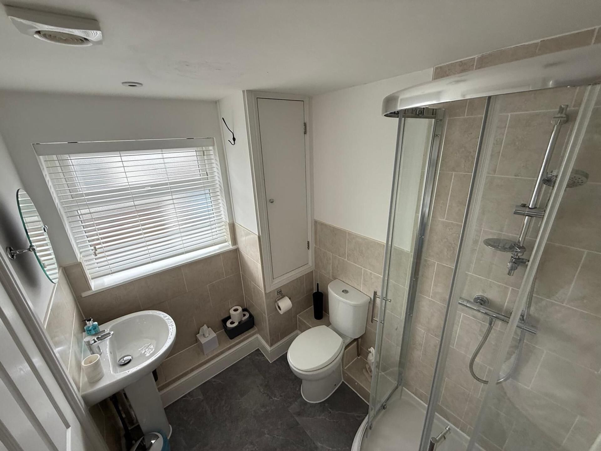 Un bagno con doccia, toilette, lavandino e finestra.
