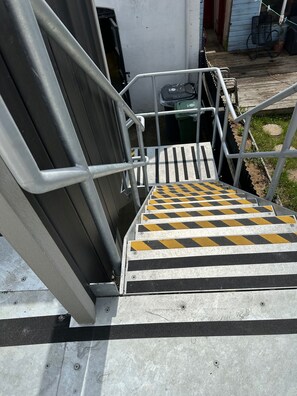 A set of metal stairs with yellow and black safety stripes leading to a building entrance. - 59a Whitstable - 1 Bedroom Flat With Balcony (Whitstable)