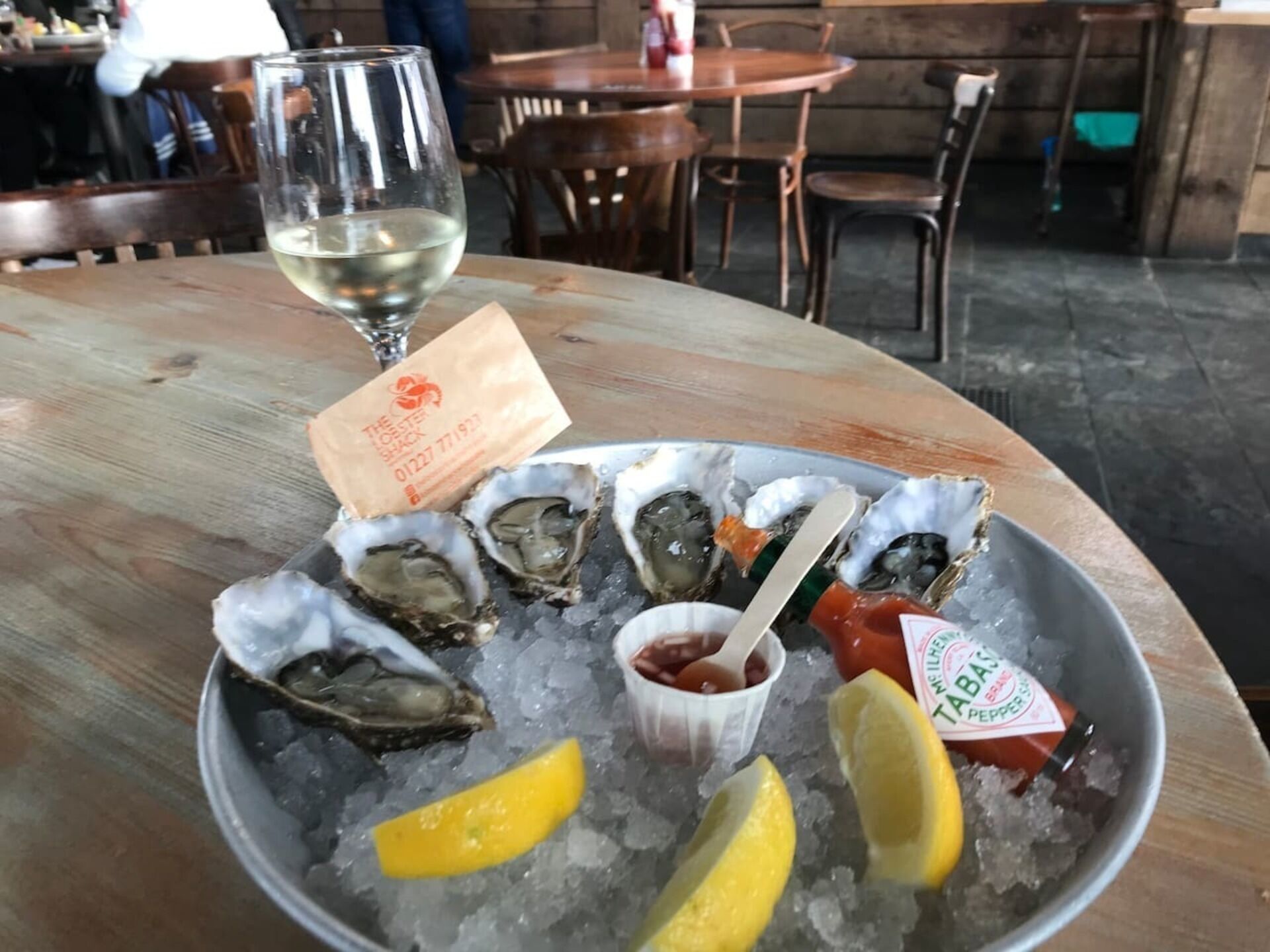 Een tafel met een bord oesters op ijs, citroenpartjes en bijgerechten.