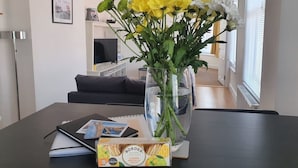 A dining table with a vase of yellow flowers, a notebook, and a box of lemon drizzle cake. - 59a Whitstable - 1 Bedroom Flat, Balcony & Parking (Whitstable)
