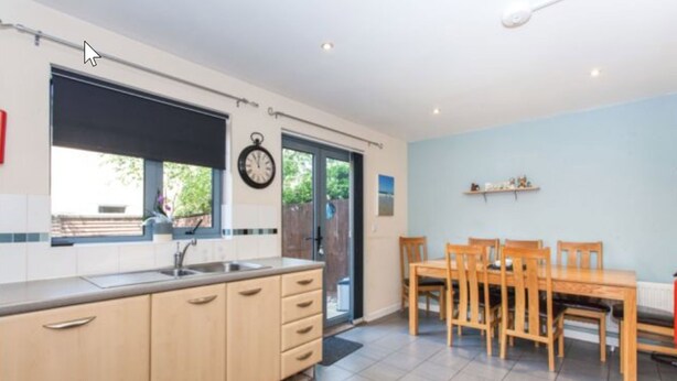 Una cocina moderna con un ventanal grande, una zona de comedor con mobiliario de madera y un reloj de pared.
