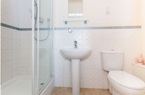 A bathroom with a glass shower enclosure, a pedestal sink, and a toilet. - Rustat Gold (Cambridge)