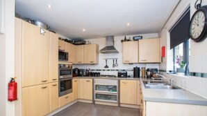 Una cocina moderna con armarios de madera clara, electrodomésticos de acero inoxidable y una isla central.