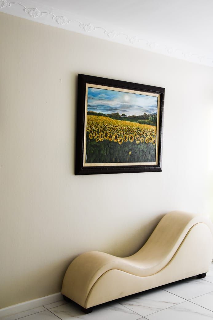 Una habitación con un cuadro enmarcado de un campo de girasoles en la pared y un banco curvo.