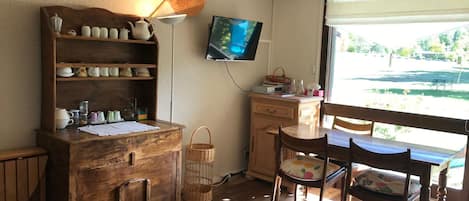 Een gezellige kamer met een houten kast, een televisie, een bureau en een raam met uitzicht op groen.