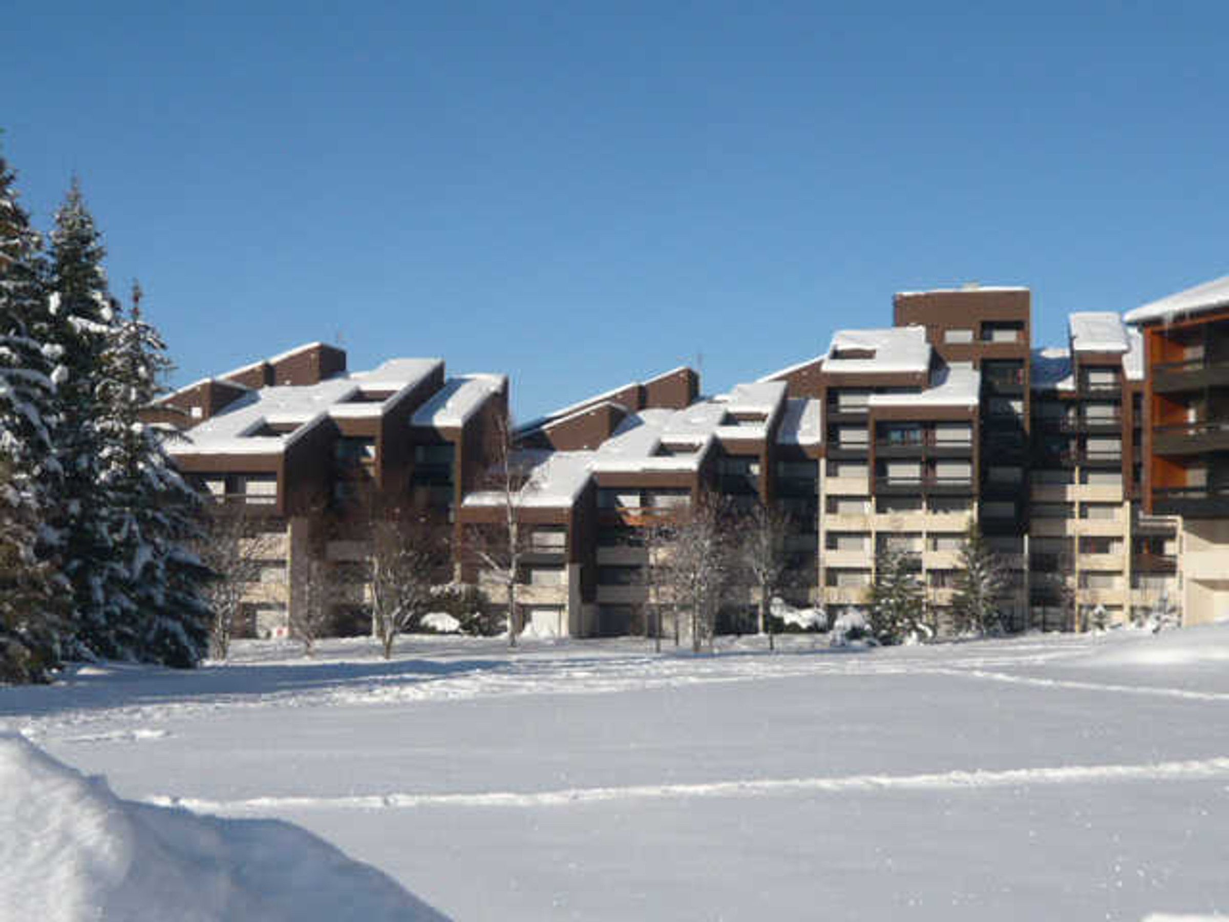 Un quartier résidentiel enneigé, avec des immeubles d’appartements modernes.