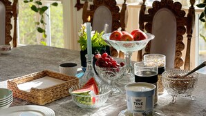 A dining table with a chandelier, a candle, fruit, and various dishes.