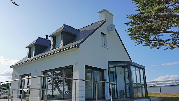 A modern building with a sloped roof, large glass windows, and a metal railing in front. - Ty Bihan, the "Little house" exceptional sea view! (Doëlan Clohars-Carnoët)