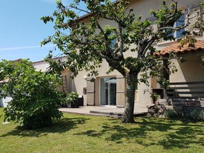 A house with a well-maintained lawn, a large tree in front, and a clear sky. - Cozy house with garden in Monts du Lyonnais (Maringes)
